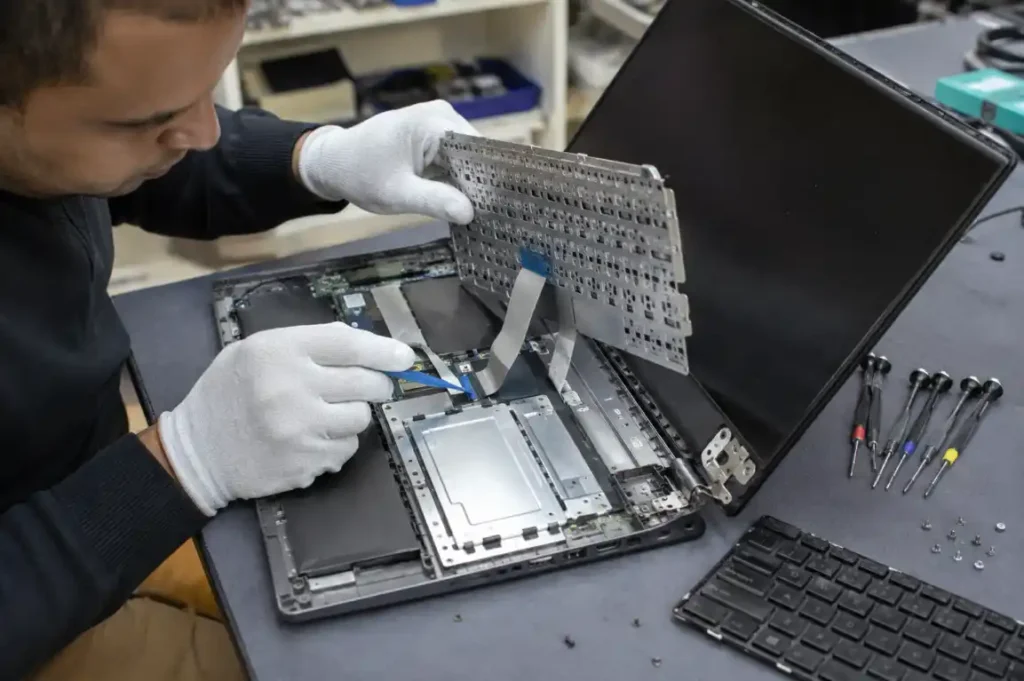 Technician repairing a laptop keyboard, touchpad and damaged hinge in Gisborne